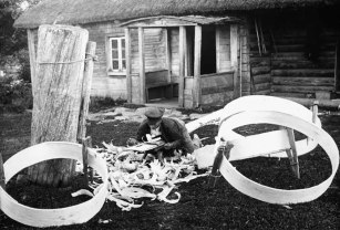 FIG. 130. Smoothing outside surface of sifter board with planing knife. Avinurme, Laurisaare village. Photograph by Vittoff, 1921. Photo library 439:163.